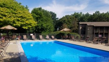 A swimming pool with chaise lounge chairs and umbrellas
